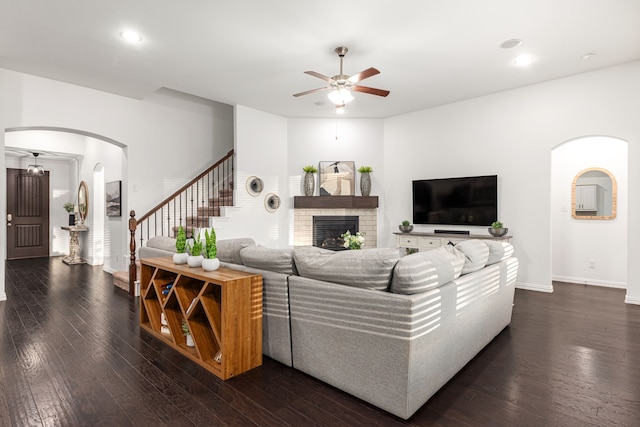 living room featuring dark wood-type flooring, a brick fireplace, and ceiling fan