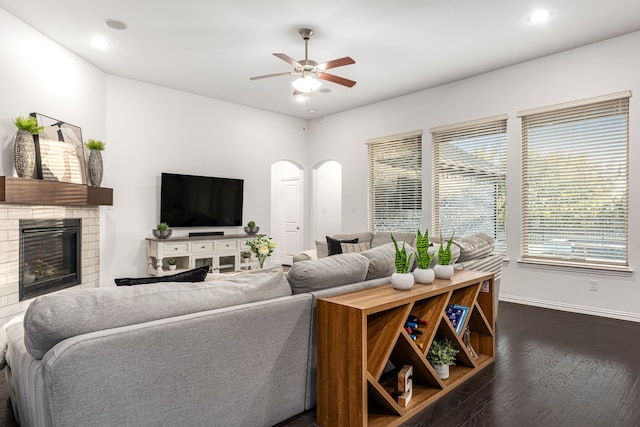 living room featuring ceiling fan, dark hardwood / wood-style flooring, and a fireplace