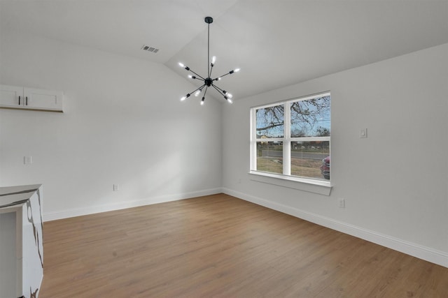 unfurnished living room featuring vaulted ceiling, an inviting chandelier, and light hardwood / wood-style floors