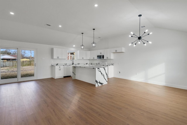 kitchen featuring white cabinetry, a breakfast bar area, wood-type flooring, vaulted ceiling, and a center island