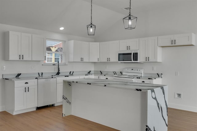 kitchen with white appliances, white cabinets, a kitchen island, decorative light fixtures, and light hardwood / wood-style floors