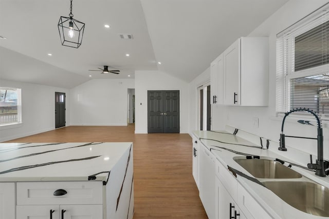 kitchen featuring lofted ceiling, wood-type flooring, sink, white cabinetry, and hanging light fixtures