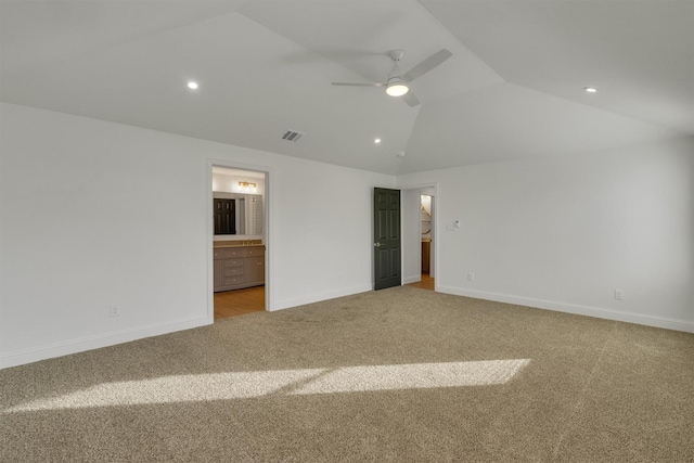 unfurnished bedroom with ceiling fan, ensuite bathroom, light carpet, and vaulted ceiling