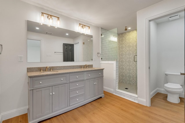 bathroom with wood-type flooring, toilet, a shower with door, and vanity