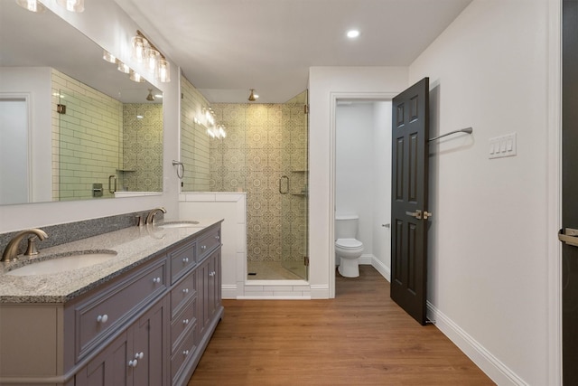 bathroom featuring an enclosed shower, vanity, wood-type flooring, and toilet