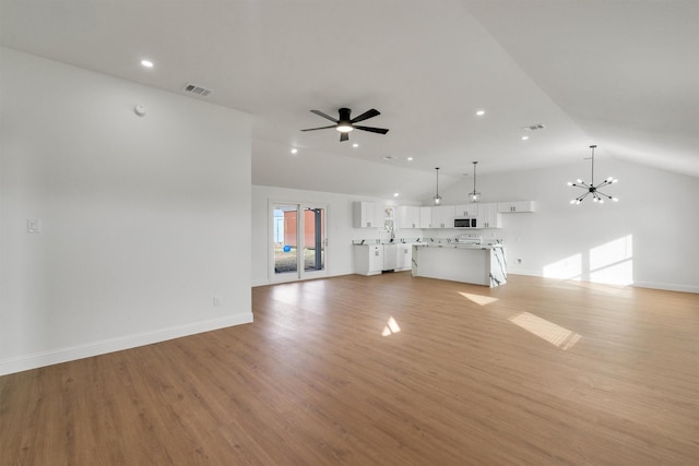 unfurnished living room with lofted ceiling, ceiling fan with notable chandelier, and light hardwood / wood-style flooring