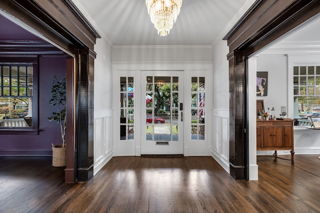 doorway to outside featuring dark wood-type flooring, ornamental molding, and an inviting chandelier