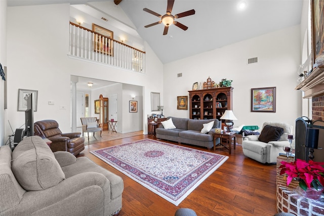 living room featuring dark hardwood / wood-style flooring, a fireplace, ceiling fan, high vaulted ceiling, and beam ceiling