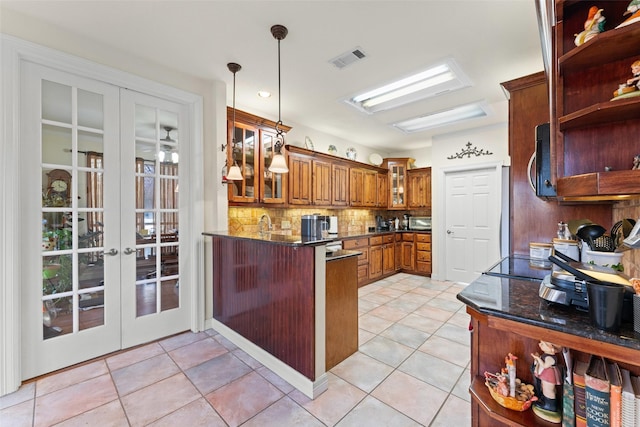 kitchen featuring light tile patterned floors, tasteful backsplash, dark stone countertops, french doors, and pendant lighting