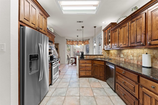 kitchen featuring pendant lighting, kitchen peninsula, sink, stainless steel appliances, and light tile patterned floors