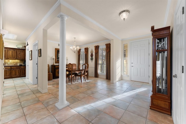 foyer entrance featuring light tile patterned floors, ornamental molding, a chandelier, and decorative columns