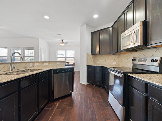 kitchen with ceiling fan, stainless steel appliances, dark hardwood / wood-style flooring, light stone countertops, and sink