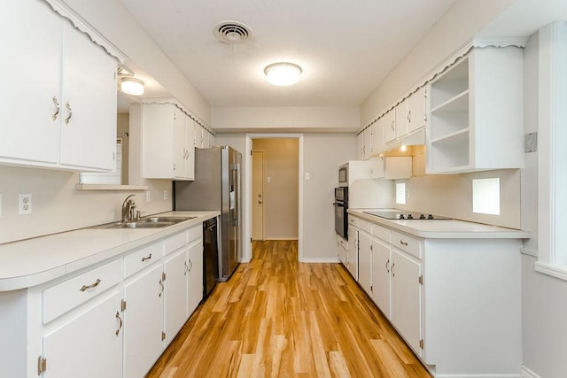 kitchen with black appliances, sink, white cabinetry, and light hardwood / wood-style flooring