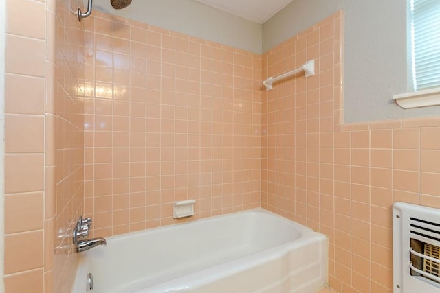 bathroom featuring tile walls, tiled shower / bath, and heating unit