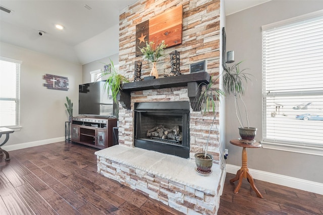 living room with a healthy amount of sunlight, dark hardwood / wood-style floors, and a stone fireplace