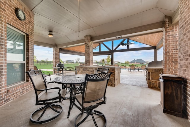 view of patio featuring exterior kitchen, a bar, and ceiling fan