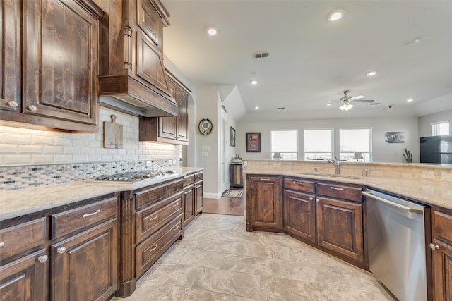 kitchen with light stone countertops, sink, appliances with stainless steel finishes, and dark brown cabinets