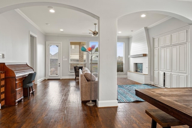 foyer with ceiling fan, dark hardwood / wood-style flooring, ornamental molding, and a fireplace