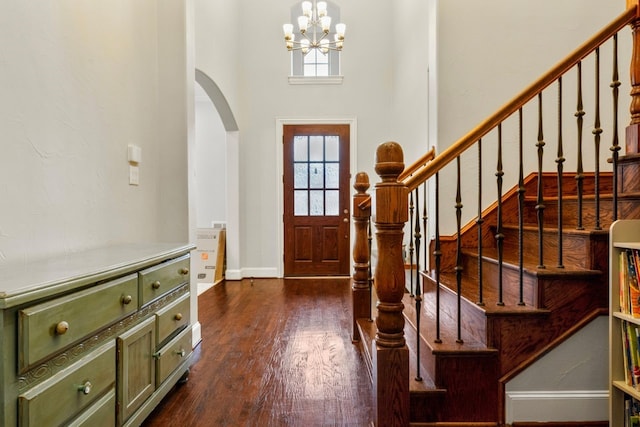 foyer entrance featuring dark hardwood / wood-style floors, a towering ceiling, and an inviting chandelier