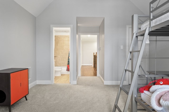 bedroom with light colored carpet, ensuite bathroom, and vaulted ceiling