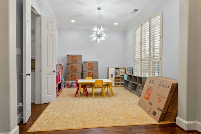 rec room featuring ornamental molding, dark hardwood / wood-style floors, and a notable chandelier