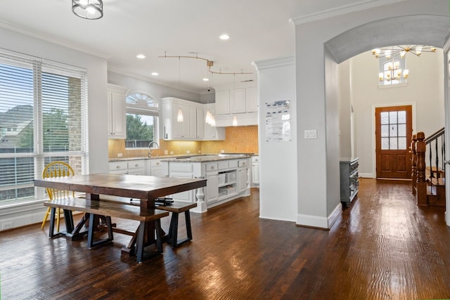 dining room featuring dark hardwood / wood-style floors, ornamental molding, and a notable chandelier