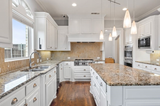 kitchen with white cabinets, a center island, stainless steel appliances, sink, and hanging light fixtures