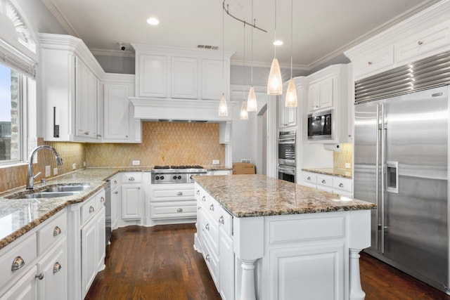 kitchen with sink, white cabinets, a center island, and built in appliances