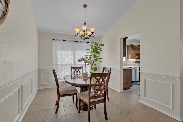 tiled dining space with vaulted ceiling, an inviting chandelier, and a textured ceiling