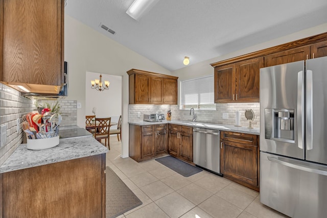 kitchen featuring light tile patterned flooring, backsplash, appliances with stainless steel finishes, and vaulted ceiling