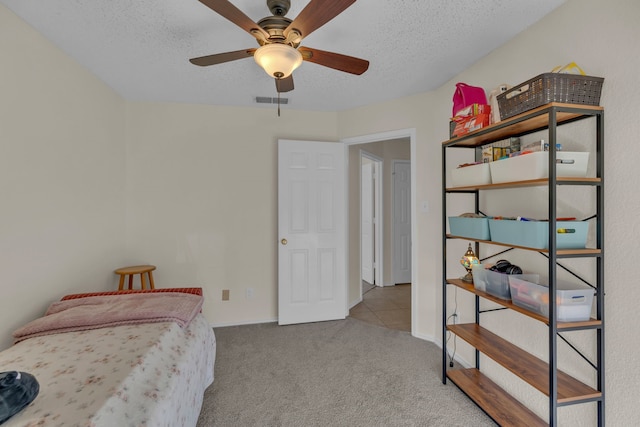 carpeted bedroom featuring ceiling fan and a textured ceiling