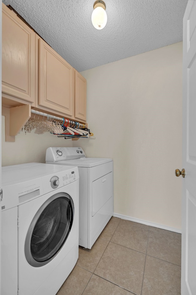 washroom featuring a textured ceiling, cabinets, light tile patterned floors, and washing machine and clothes dryer