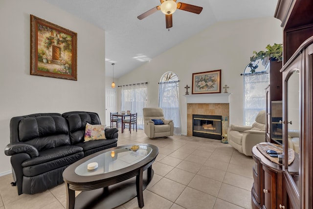 living room with ceiling fan, vaulted ceiling, light tile patterned flooring, and a tile fireplace