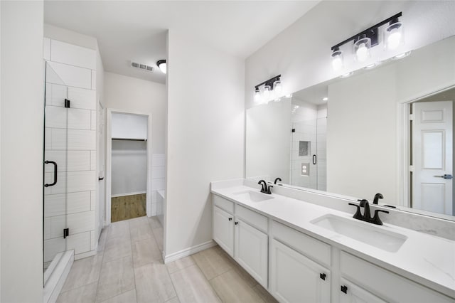 bathroom featuring a shower with door and vanity