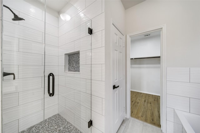 bathroom featuring tile patterned flooring, tile walls, and an enclosed shower