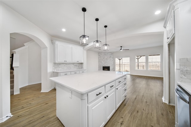 kitchen with light hardwood / wood-style floors, tasteful backsplash, a fireplace, hanging light fixtures, and white cabinets