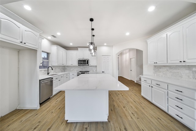 kitchen with hanging light fixtures, white cabinets, stainless steel appliances, and a kitchen island