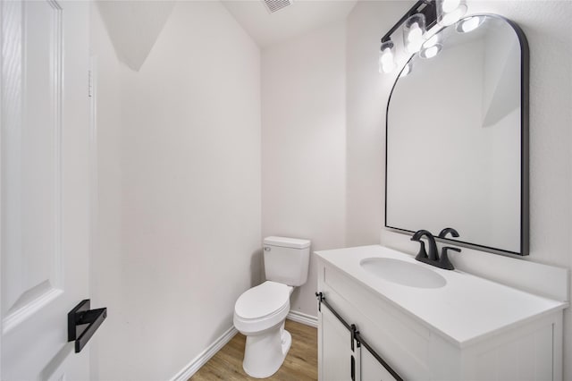 bathroom with toilet, vanity, and wood-type flooring