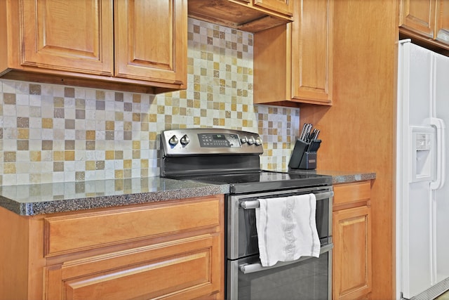 kitchen with backsplash, white refrigerator with ice dispenser, and range with two ovens