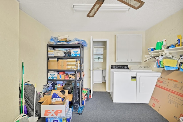 laundry room featuring a textured ceiling, separate washer and dryer, and cabinets