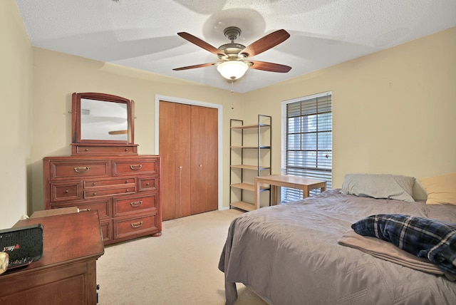 carpeted bedroom with a textured ceiling, ceiling fan, and a closet