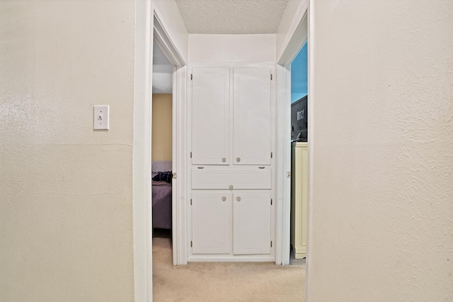 hall featuring a textured ceiling and light colored carpet