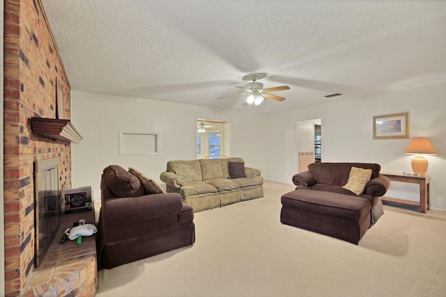 living room featuring ceiling fan, light colored carpet, a brick fireplace, and a textured ceiling