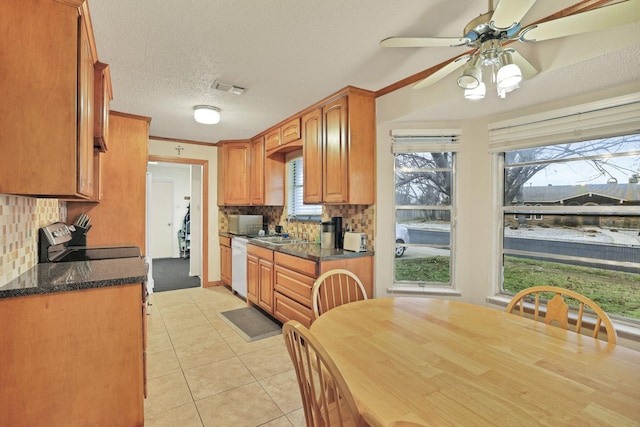 kitchen featuring a textured ceiling, dishwasher, tasteful backsplash, sink, and light tile patterned flooring