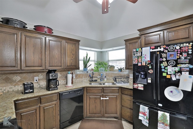 kitchen with sink, tasteful backsplash, light stone counters, and black appliances