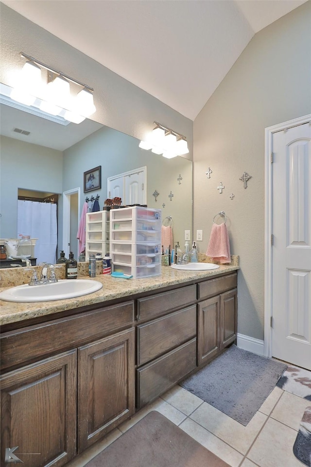 bathroom with tile patterned flooring, lofted ceiling, and vanity