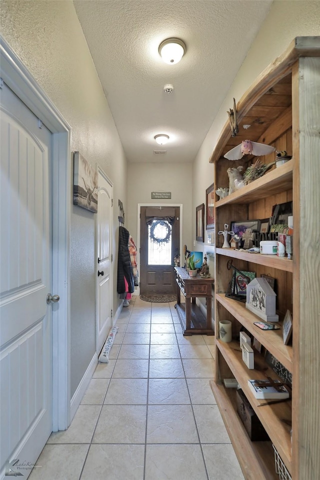 doorway featuring a textured ceiling and light tile patterned flooring