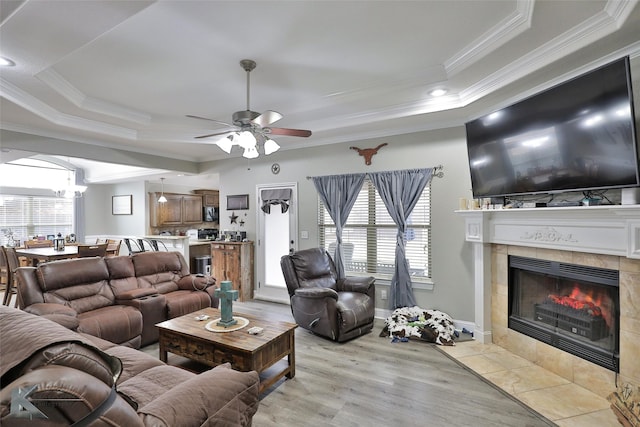 living room featuring a tray ceiling, light hardwood / wood-style flooring, crown molding, and a fireplace