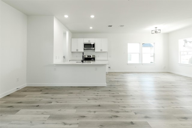 unfurnished living room featuring sink and light hardwood / wood-style floors