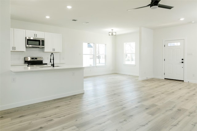 unfurnished living room with ceiling fan, sink, and light hardwood / wood-style floors